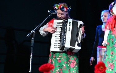 Podopieczna M-Gok ubrana w str&oacute;j ludowy grająca na akordeonie. 